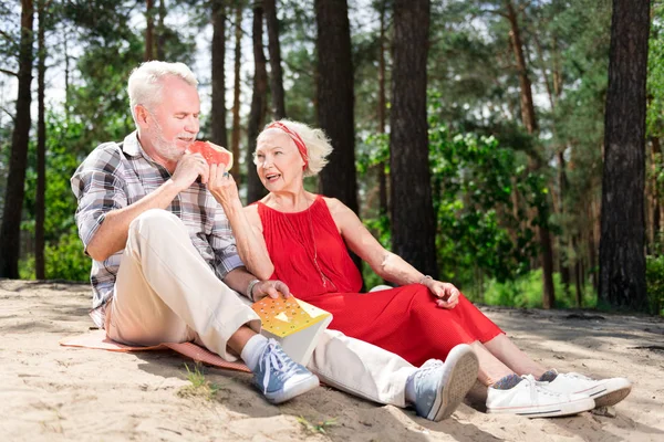 Lindos pensionistas con zapatillas comiendo sandía durante el picnic — Foto de Stock