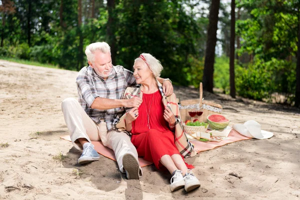 Fürsorglicher älterer Mann legt Schottenkaro auf die Schultern seiner Frau — Stockfoto