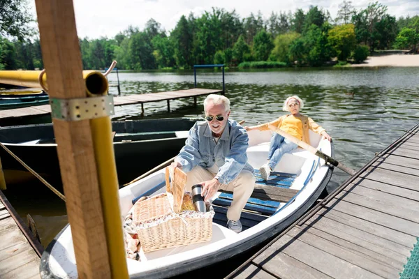 Chilling in boat. Elderly man and woman wearing sunglasses chilling in little boat on amazing weekend