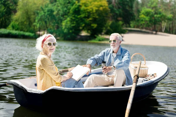 Feliz anciana leyendo libro durante increíble paseo en barco con su hombre — Foto de Stock
