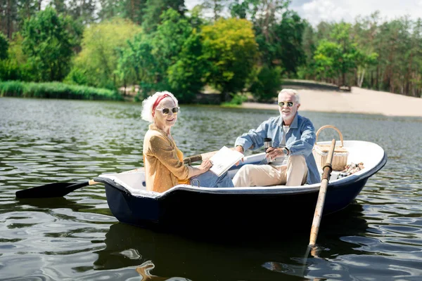 Beaming fashionable pensioners having snack during their boat ride — Stock Photo, Image