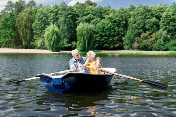 Aged wife and husband holding paddles having nice river trip in boat — Stock Photo, Image