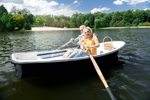 Пожилая женщина взволнована, держа весло в лодке — стоковое фото