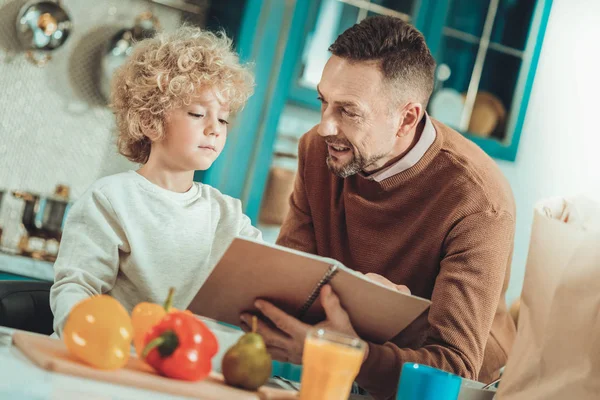 Père et fils vérifiant une recette dans un carnet — Photo