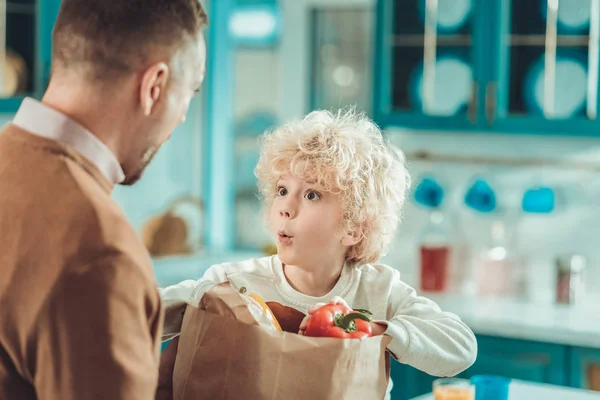 Geschokt kind op zoek naar vader met nieuwsgierigheid — Stockfoto