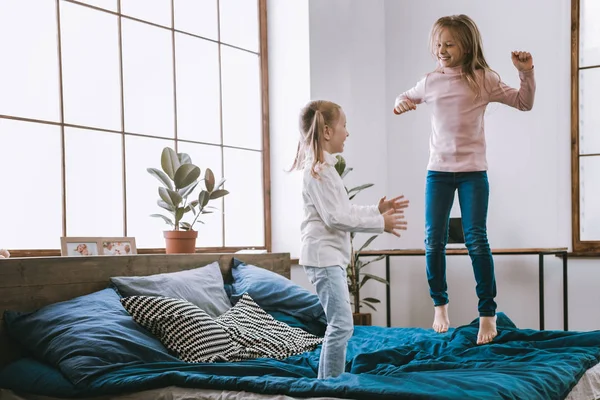 Vrolijke happy meisjes springen op het bed — Stockfoto