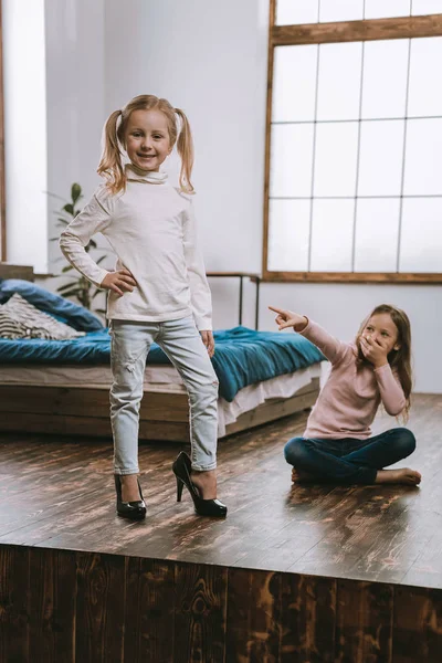 Freudiges nettes Mädchen zeigt auf ihre Schwester — Stockfoto