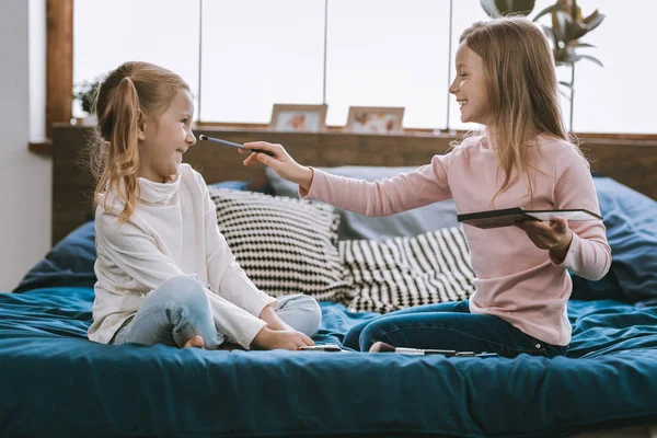 Gelukkig mooi meisjes zitten op het bed — Stockfoto