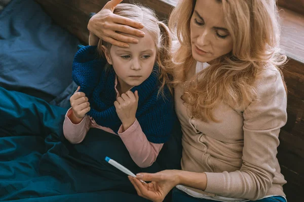 Nette ernste Frau hält ihre Töchter auf die Stirn — Stockfoto