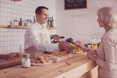 Ayakta ve bir kredi kartı alarak keyifli yakışıklı adam.