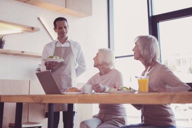 Ayakta ve bir çanak tutan özenli yakışıklı.