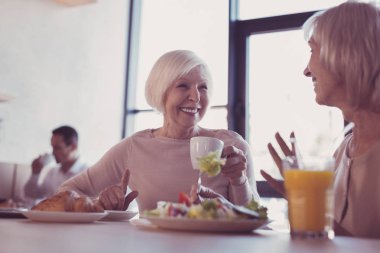 Gülümseyen ve bir fincan tutan memnun hoş kadın.