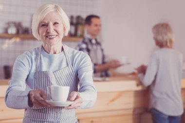 Ayakta ve bir fincan holding neşeli samimi kadın.