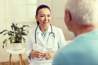 Üst düzey hastayla konuşuyor ve gülümseyen neşeli hekim