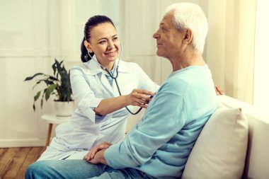 Neşeli Doktor stetoskop yaşlı adamın akciğerleri kontrol etmek için kullanma