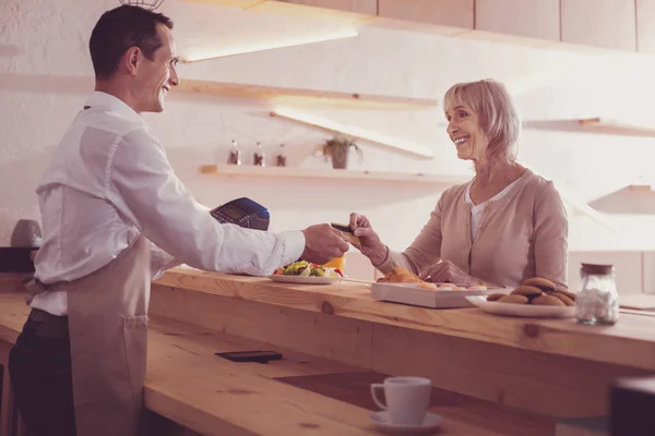 Mujer mayor satisfecha sonriendo y tomando una tarjeta de crédito . —  Fotos de Stock