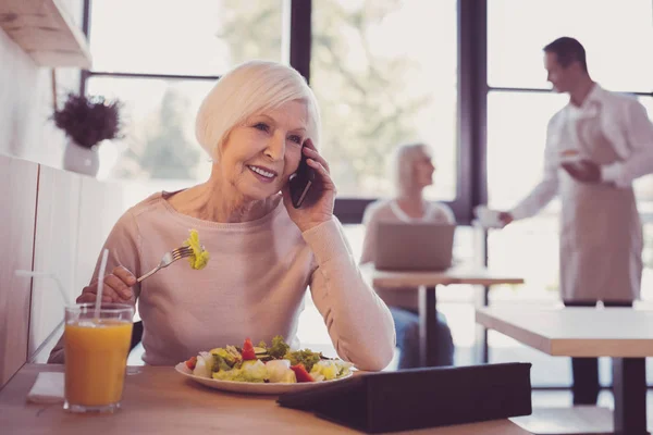 笑顔の忙しい女性を食べると、ヘットの携帯電話を使用して. — ストック写真