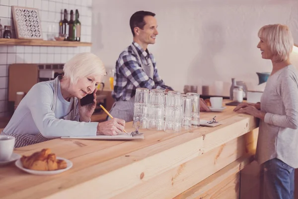 Mujer responsable concentrada escribiendo y conversando . — Foto de Stock