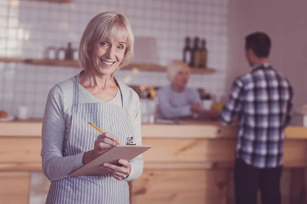 Agradable mujer satisfecha de pie y tomando notas . —  Fotos de Stock