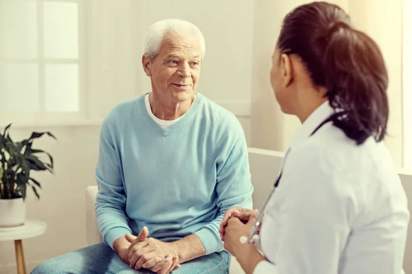 Amigável olhando aposentado homem sorrindo enquanto ouve o médico — Fotografia de Stock