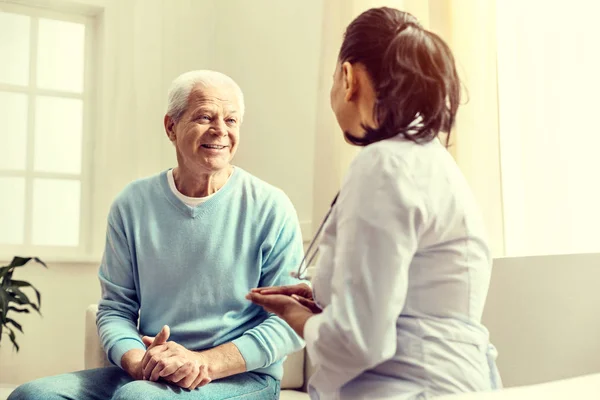 Веселый пожилой джентльмен консультируется с медсестрой — стоковое фото