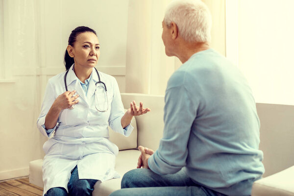 Заботливая медицинская работница разговаривает со старшим пациентом
