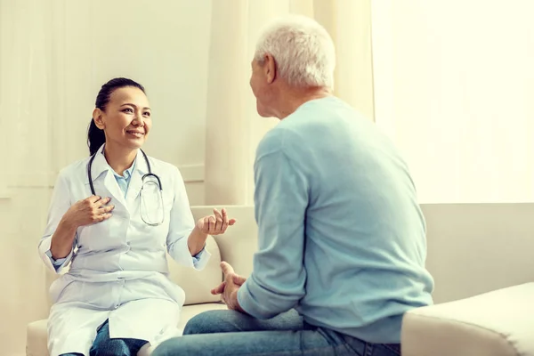 Дружній лікар посміхається під час консультації з пенсіонером — стокове фото
