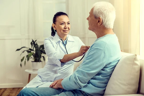 Усміхнена медсестра слухає серцебиття пацієнта у відставці — стокове фото
