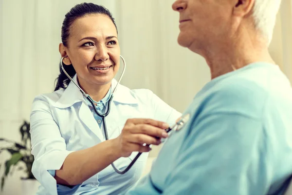 Stralend vrouwelijke arts luisteren naar hart gewonnen — Stockfoto