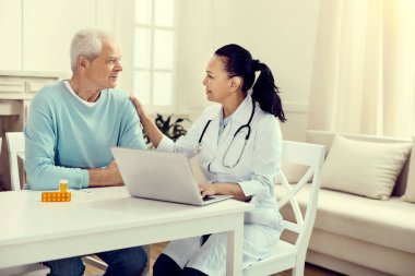 Yaşlı adam için Danışma sırasında konuşurken dost görünümlü doktor