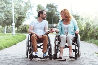 Seven olgun çift birlikte tekerlekli sandalye otururken elele