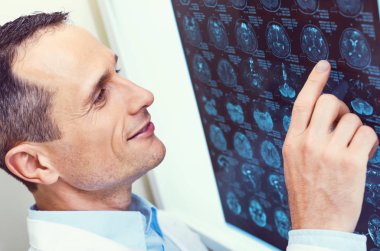 Bilgisayarlı tomografi taraması bakarken gülümseyen pozitif fikirli doktor