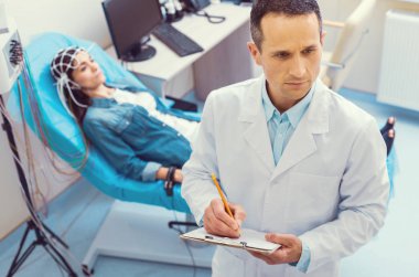 Ciddi Doktor elektroansefalografi işlem sırasında notlar almak