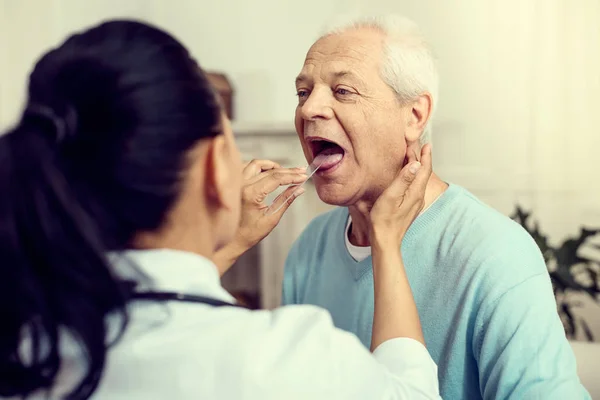 Infermiera utilizzando bastone medico durante il controllo della gola del paziente — Foto Stock