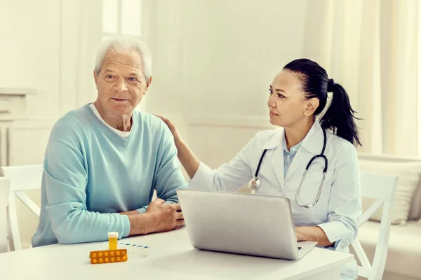 Försiktig kvinnlig sjuksköterska lugnande ledsen äldre patient — Stockfoto