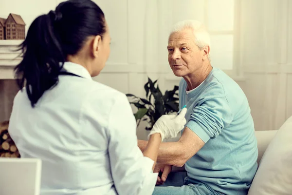 Paciente mayor mirando al médico vacunándolo — Foto de Stock