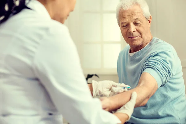 Pensionist schaut Krankenschwester beim Impfen zu — Stockfoto