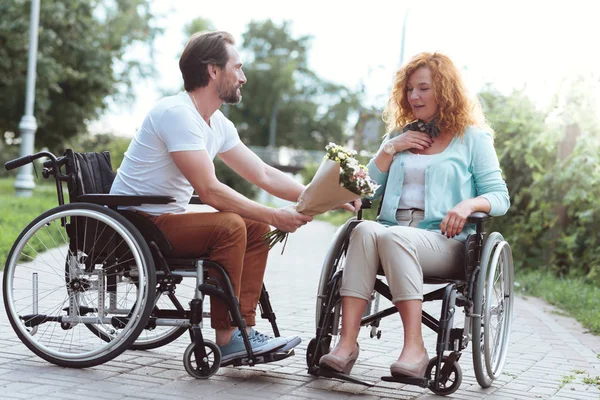 Homme handicapé réfléchi surprenant son âme soeur avec des fleurs — Photo