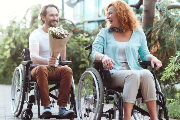Glada kvinna emot bukett när du kör sin rullstol — Stockfoto