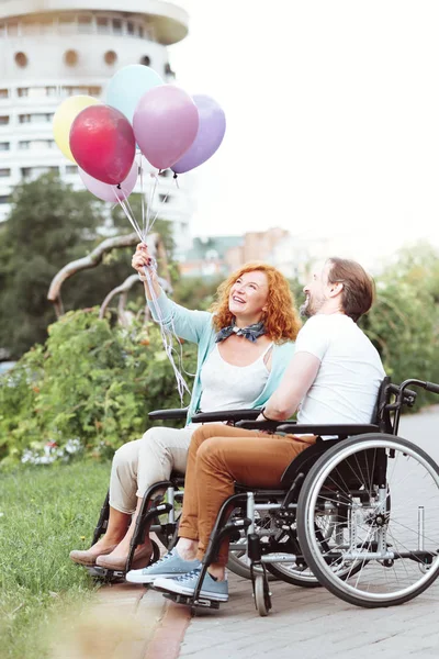 Pareja armoniosa sonriendo mientras mira globos coloridos — Foto de Stock