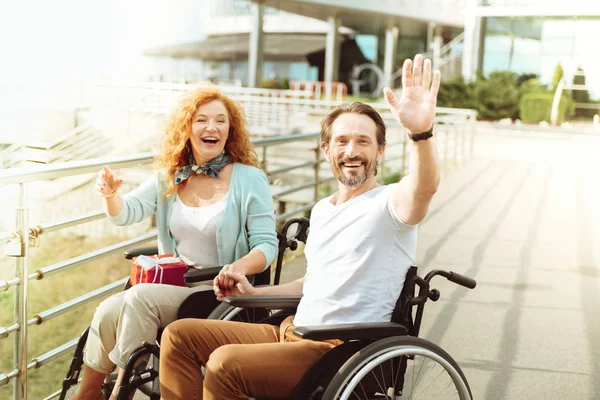 Friendly couple in wheelchairs welcoming a stranger — Stock Photo, Image