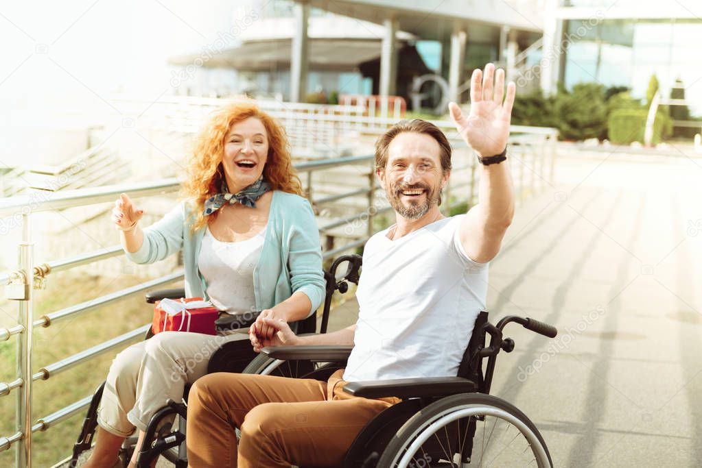Friendly couple in wheelchairs welcoming a stranger