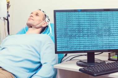 PC displaying brain waves of male patient at lab clipart