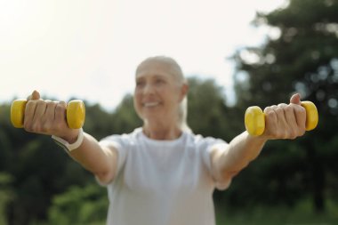 Neşeli kadın kıdemli açık havada halter kaldırma