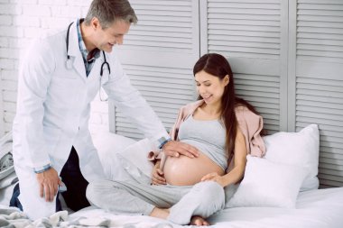 El bir karnına koyarak olumlu neşeli doktor