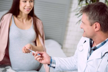 Tıbbi malzeme. Hamile, güzel bir genç kadın için verilen varlık bir elektronik termometre seçici odak