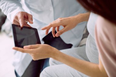 Dijital aygıt. Pozitif güzel hamile bir kadın tarafından doktoruyla konuşurken kullanılan modern bir tablet yakın çekim