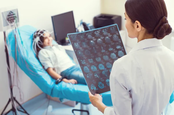 Young radiologist analyzing computed tomography scan of little girl — Stock Photo, Image