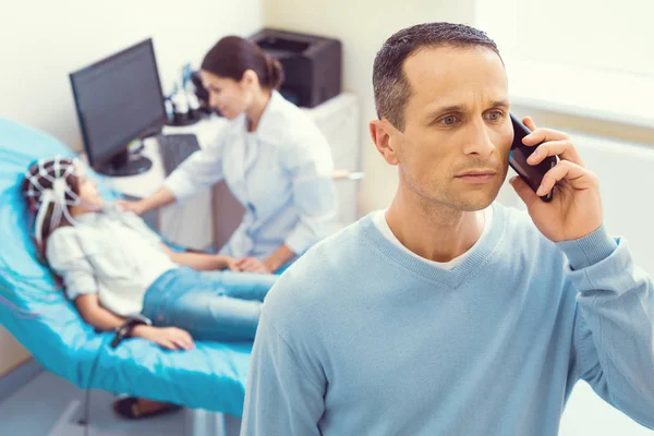 Padre spaventato che parla al telefono mentre la figlia subisce l'elettroencefalografia — Foto Stock