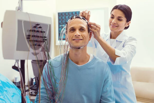 Cheerful doctor adjusting electrodes before electroencephalography analysis — Stock Photo, Image